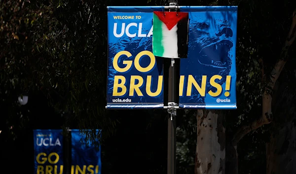 A Palestinian flag is placed over a university banner near an encampment to protest the Israel-Hamas war on the UCLA campus Tuesday, April 30, 2024, in Los Angeles. (AP)