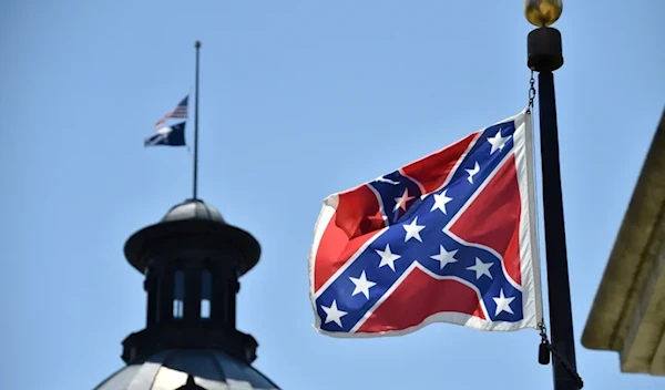 The South Carolina and American flags fly at half-staff behind the Confederate flag, in front of the State House in Columbia, South Carolina on June 19, 2015. (AFP)