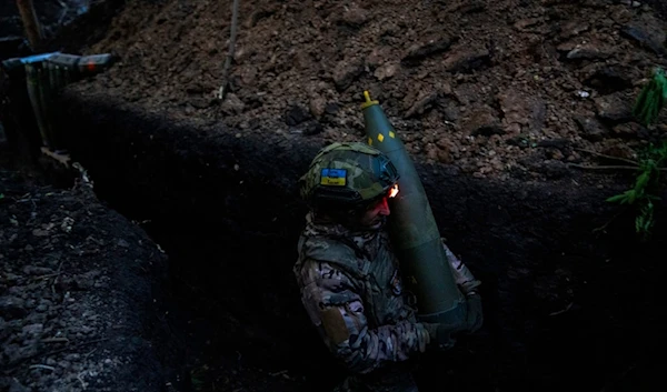 A Ukrainian serviceman of 148th separate artillery brigade of the Air Assault Forces of the Armed Forces of Ukraine carries a shell in Donetsk front, Ukraine, Tuesday, May 7, 2024. (AP)