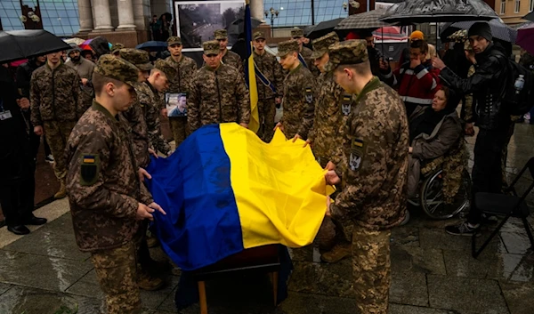 Honor guards salute place an Ukrainian flag onto the coffin of Ukrainian army paramedic killed in the war, during his funeral ceremony at Independence square in Kiev, Wednesday, April 24, 2024. (AP)