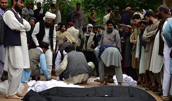 The bodies of Afghans killed in the floods are placed on the ground in Baghlan province, northern Afghanistan, on Saturday. (AP)