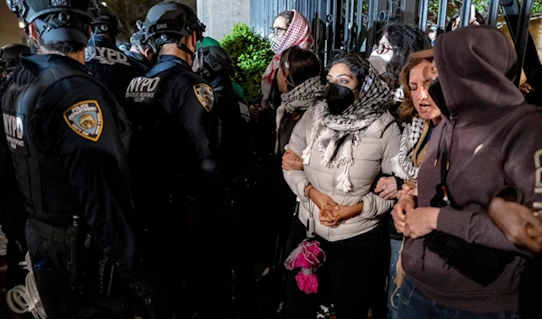 Demonstrators lock arms near a main gate at Columbia University in New York Tuesday, April 30, 2024, as New York City police officers move to clear the area. (AP)