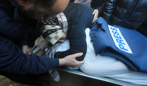 A relative mourns Palestinian journalist Akram Al-Shafi'i, killed in the Israeli bombardment of the Gaza Strip, in a morgue of the European Gaza Hospital in Rafah, occupied Palestine, January 6, 2024 (AP)