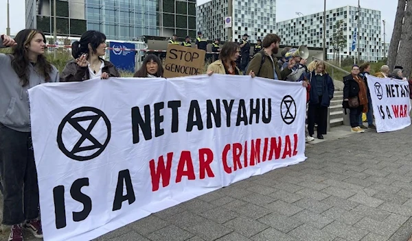 Activists hold up a banner denouncing Israeli Prime Minister Benjamin Netanyahu for Israeli genocide against Palestinians in Gaza as they demonstrate at the entrance of the International Criminal Court in The Hague, Netherlands, Monday, Oct. 23, 2023. (AP)