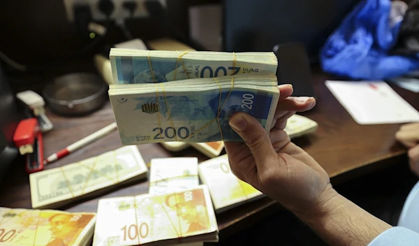 A man holds Shekel paper bills in an undated photo (AFP/Getty)