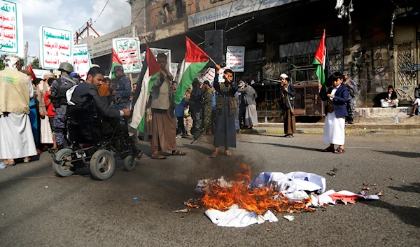 Protesters burn representation of the US and Israeli flags in Sanaa, Yemen, July 4, 2023 (AP)