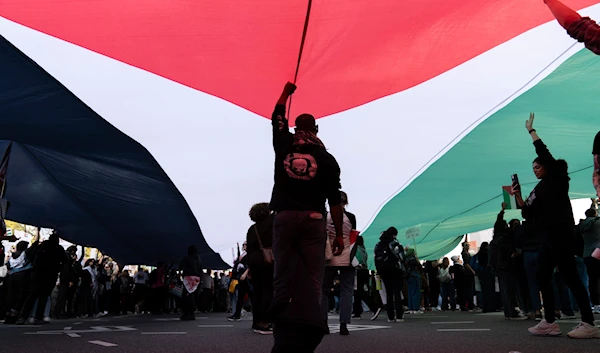 Anti-war activists hold a Palestinian flag during a pro-Palestinian demonstration asking for a cease-fire in Gaza, at Freedom Plaza in Washington, Saturday, Nov. 4, 2023. (AP)