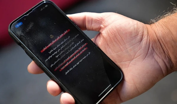 A mobile phone displays an Israeli alert warning residents of southern Lebanon not to return to their homes until further notice in Beirut, Lebanon, Wednesday, Oct. 9, 2024. (AP)