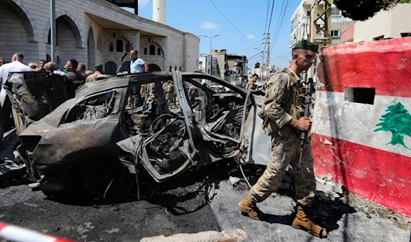 A Lebanese Army soldier passes in front of a car that was hit by an Israeli strike in the southern port city of Sidon, Lebanon, Wednesday, August 21, 2024 (AP)