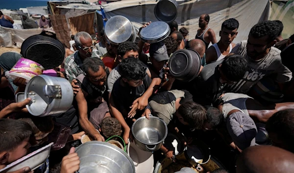 Displaced Palestinians at a food distribution center in Deir al Balah, central Gaza Strip, Friday, Aug. 23, 2024. (AP Photo/Abdel Kareem Hana)