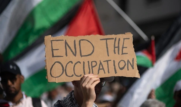 A Moroccan man carries a sign during a protest in support of Gaza and Lebanon, in Rabat, Morocco, Sunday, October 6, 2024 (AP)