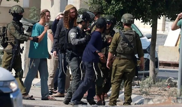 Israeli soldiers restrain Jewish settlers after they stormed the Palestinian West Bank village of Dayr Sharaf. (AFP)