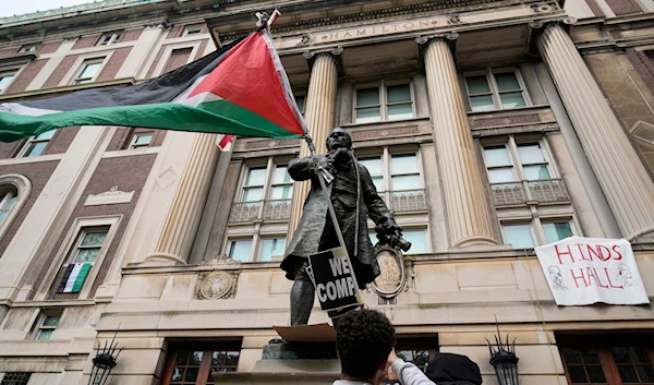 A student protester parades a Palestinian flag outside the entrance to Hamilton Hall on the campus of Columbia University, on April 30, 2024, in New York. (AP)