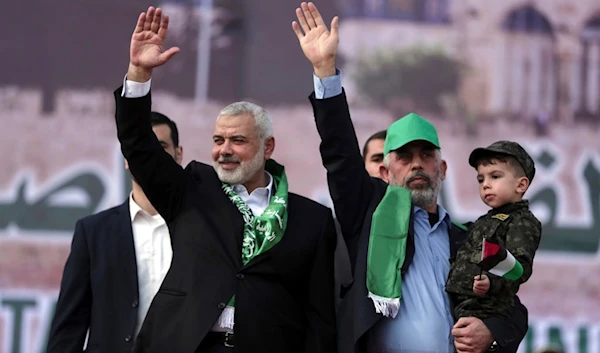 Martyred Head of the Hamas political bureau, Ismail Haniyeh, left, and Hamas leader in the Gaza Strip Yahya Sinwar, wave their hands during a Rally marking the 30th anniversary of their group, in Gaza City, Dec. 14, 2017. (AP)