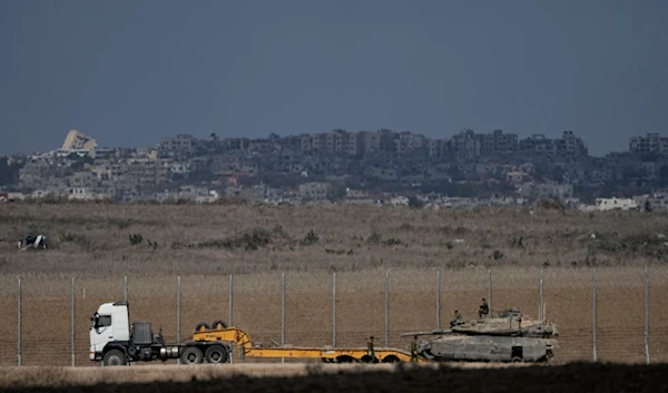 Israeli soldiers lode a tank onto a truck on the separation line with Gaza, as seen from southern occupied Palestine, Friday, Oct. 18, 2024. (AP Photo/Tsafrir Abayov)