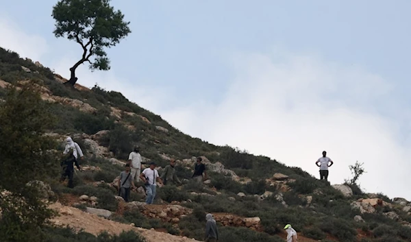 Armed Israeli settlers gather on a hill overlooking the village of Mughayir near Ramallah in the Israeli West Bank on April 13,2024.(AFP)