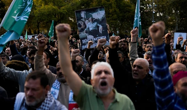 People hold up a poster with a photograph of Hamas leader Yahya Sinwar, who was martyred in Gaza on Wednesday in Istanbul, Turkey, Saturday, October 19, 2024 (AP)