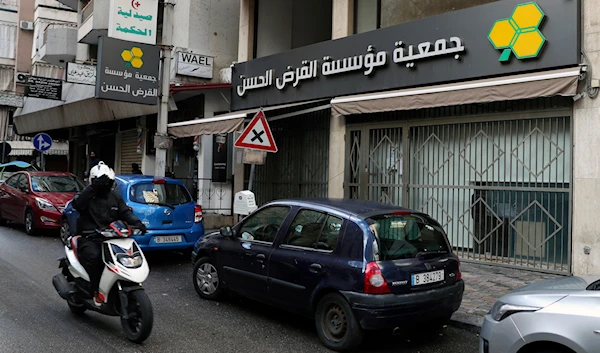 A man on a scooter passes a branch of the al-Qard al-Hassan Association, in Beirut, Lebanon, on January  20, 2021.