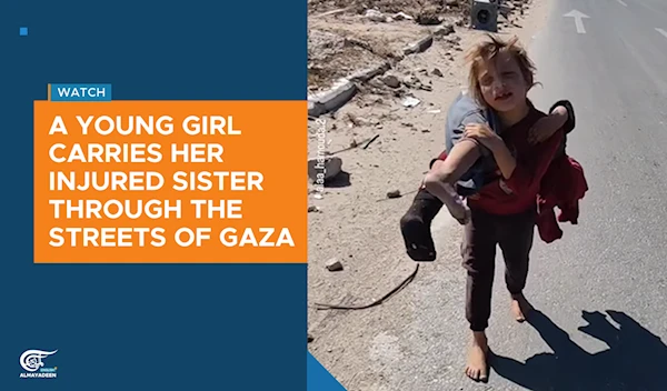 A young girl carries her injured sister through the streets of Gaza