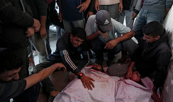 Palestinians mourn their relatives killed in the Israeli bombardment of the Gaza Strip at a hospital in Deir el-Balah, Sunday, Oct. 20, 2024. (AP)