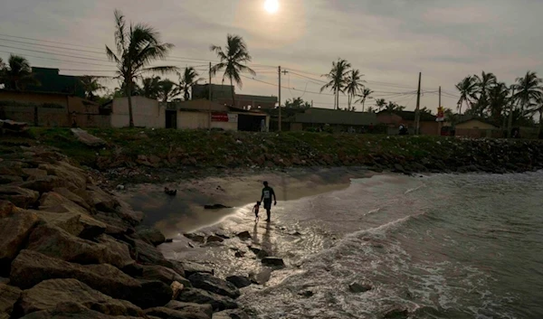 A man walks on the beach with his child in Colombo, Sri Lanka, Thursday, Jan. 12, 2023. (AP Photo/Eranga Jayawardena)