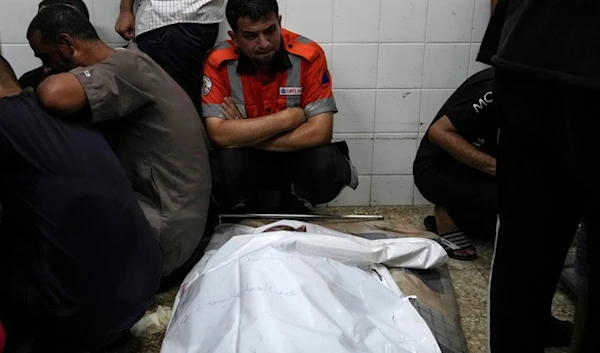 Palestinians mourn their colleague civil defense member killed in the Israeli bombardment of Nuseirat refugee camp, at the morgue of al-Aqsa Martyrs Hospital in Deir al Balah, central Gaza Strip, late Thursday, June 27, 2024 (AP)