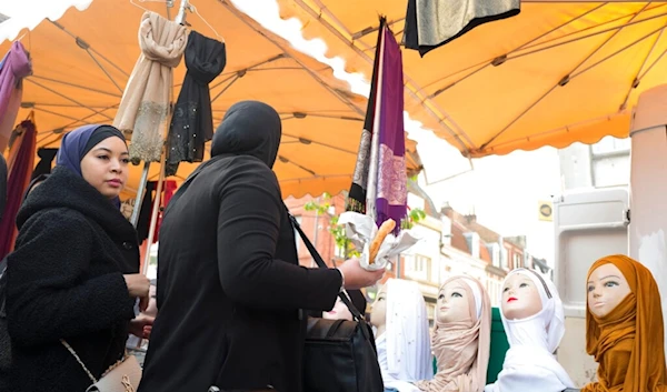 A woman watches mannequins presenting Muslim veils at an open air market in Lille, northern France, Thursday, Oct. 31, 2019. (AP)