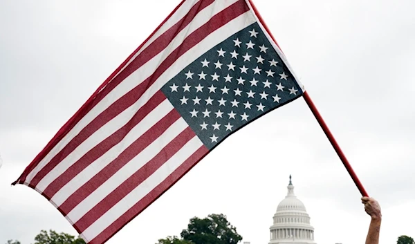 With the U.S. Capitol in the background, a demonstrator waves an upside down American flag before a rally in Washington, Saturday, Sept. 18, 2021. (AP)