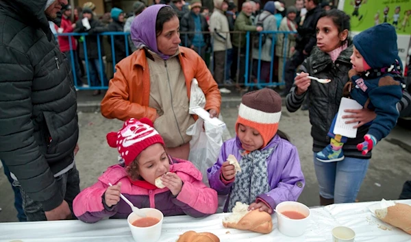 In this Wednesday, Dec. 16, 2015 file photo, homeless children eat as others wait in line for their turn outside the main railway station in Bucharest, Romania. (AP)