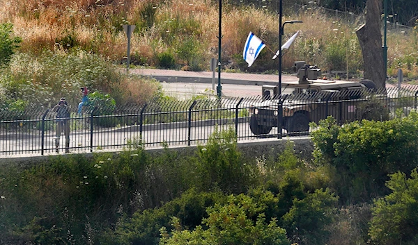 An Israeli soldier looks through binoculars as he stands on a perimeter road in the town of Metula on the Israeli side of the Lebanese-Israeli border, near the southern Lebanese village of Kfar Kila, Lebanon, Sunday, May 29, 2022.