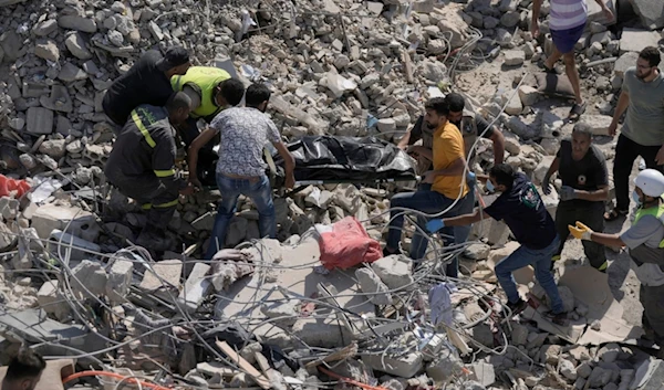 Rescue workers carry the body of a victim found under the rubble of a destroyed building that was hit Tuesday night in an Israeli airstrike, in Sarafand, south Lebanon, Wednesday, Oct. 30, 2024. (AP)