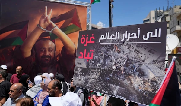 A protester holds a sign reading, "To the free people of the world, Gaza is being exterminated,",  a high-profile Palestinian prisoner, during a rally supporting Gaza and prisoners held by 'Israel 'in Ramallah, West Bank, Palestine, Aug. 3, 2024. (AP)