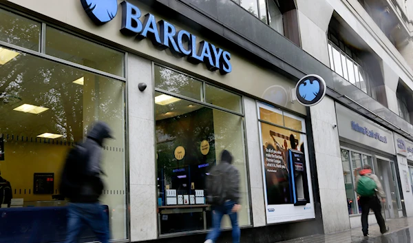 Pedestrians pass a branch of Barclays Bank in the rain in London, on May 8, 2014. (AP)