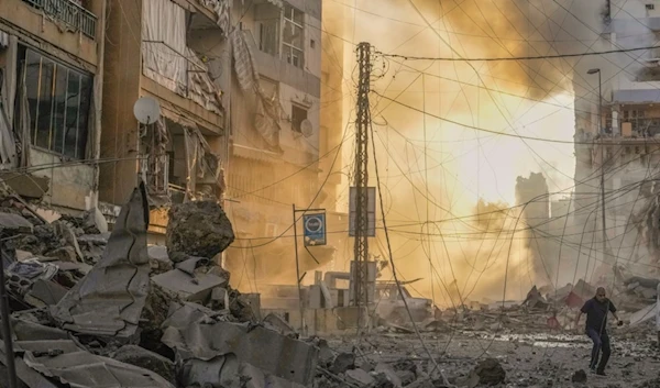 A man runs for cover as a smoke raises in the background following an Israeli airstrike in Dahiyeh, Beirut, Lebanon, Friday, Oct. 4, 2024. (AP)