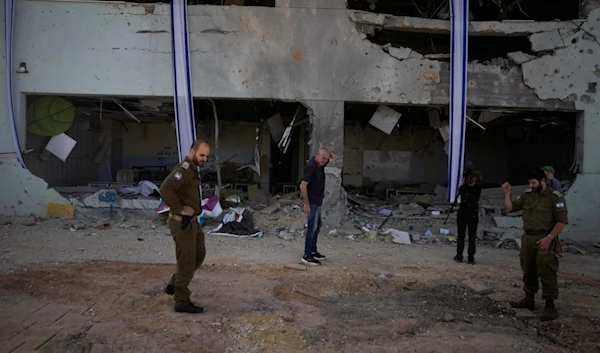 Israeli military and people look at a damaged building that was hit in Iran's missile attack in "Gedera", occupied Palestine, Wednesday, Oct. 2, 2024. (AP Photo/Ohad Zwigenberg)