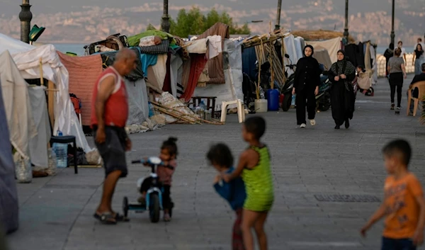 People walk past tents set up as temporary shelters by displaced families fleeing the Israeli airstrikes in the south and Dahiyeh, on Beirut's corniche, Lebanon, Monday, Oct. 14, 2024. (AP)