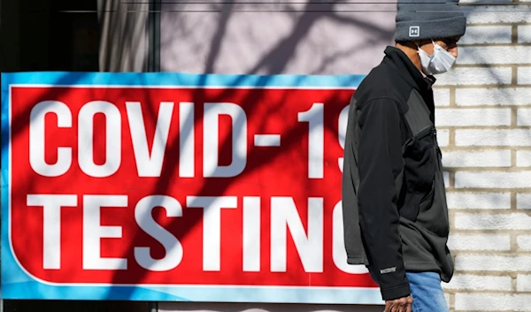 Covid test sign is displayed at a store as a pedestrian walks past in Chicago, Monday, March 11, 2024. (AP Photo/Nam Y. Huh)