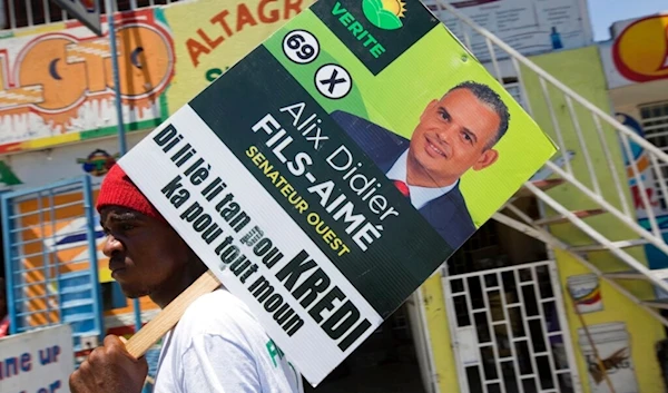 A supporter of the political party Platform Vérité carries a poster of parliamentary candidate Alix Didier Fils-Aime in Port-au-Prince, Haiti, Friday, Aug. 7, 2015. (AP)