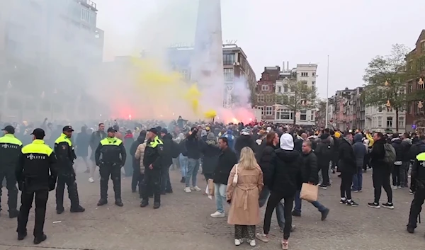 Police stand guard as Maccabi Tel Aviv supporters light flares at the Dam square, in Amsterdam, the Netherlands, on November 7, 2024. (AP)