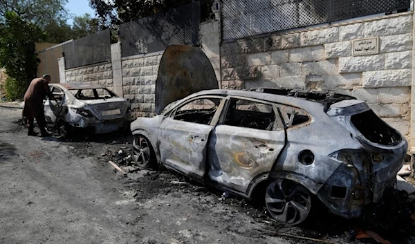 A Palestinian examines a torched vechile, seen the morning after a rampage by Israeli settlers in the West Bank village of Jit, on August 16,2024.(AP)