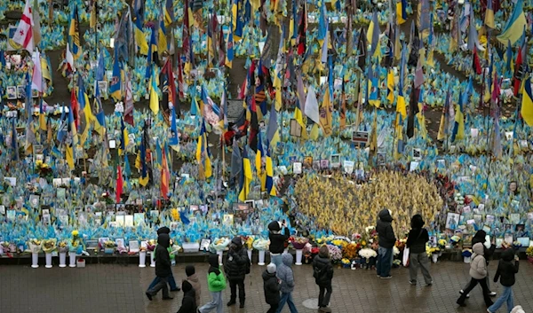 People walk past the memorial to fallen soldiers in Independence Square in Kyiv, Ukraine, Friday, Nov. 15, 2024. (AP Photo/Efrem Lukatsky)