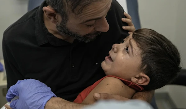 Hassan Mikdad, holds his son Hussein Mikdad, who was injuired on Oct. 2 in an Israeli airstrike at a densely-populated neighborhood south of Beirut, as he cries during a check up by his doctor, on November 5,2024. (AP)