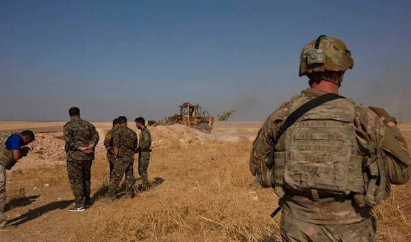 In this September 6, 2019, photo, a US special forces soldier and Kurdish fighters watch a bulldozer dismantle a fortification in the so-called "safe zone" on the border with Turkey near Tal Abyad, Syria (AP)