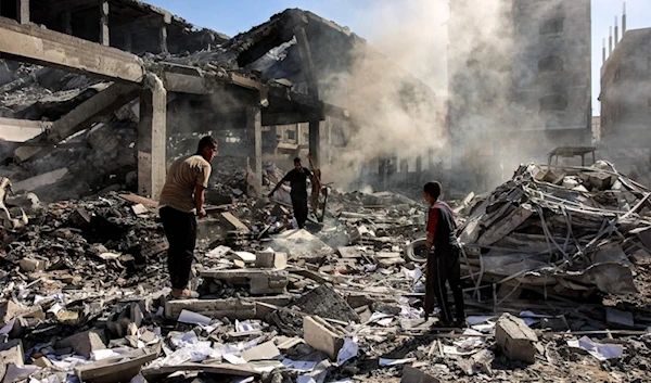 Palestinians walk through debris in a residential building bombed by "Israel" in the Sheikh Radwan neighborhood in the north of Gaza City, September 3, 2024. (AFP)