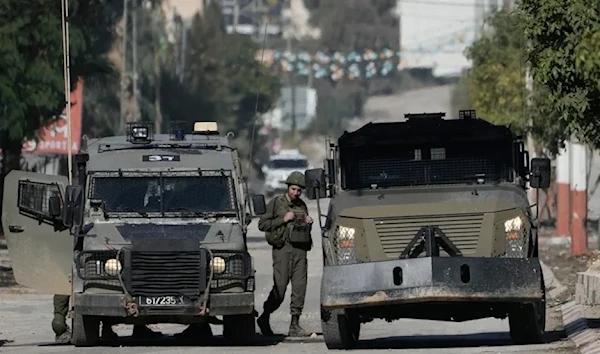 An Israeli occupation soldier stands by a vehicle during a raid in the West Bank of Jenin, on November 20, 2024. (AP)