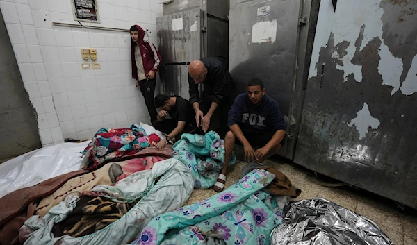 Palestinians mourn over relatives killed in an Israeli bombardment in Nuseirat, central Gaza, as they stand in a hospital morgue in Deir al-Balah, Gaza Strip, on November 20, 2024. (AP)