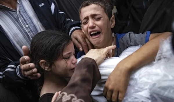 Palestinian children crying while holding the body of their mother who was killed in an Israeli airstrike on Gaza in November 2023. (AP)