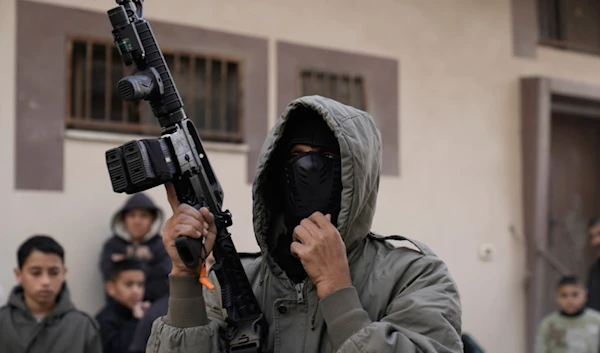 A Palestinian resistance fighter attends the funeral of Mohammad Hamarsheh, 13, and Ahmad Zaid, 20, killed during an Israeli military raid in the village of Yabad near the West Bank city of Jenin, Monday, November 25, 2024 (AP)