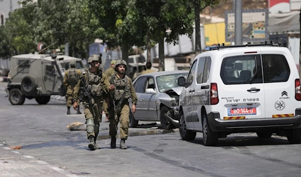 Israeli soldiers work at the site of an alleged car-ramming operation near Beit Hagai, a Jewish settlement in the hills south of al-Khalil, Aug. 30, 2023. )ِ؛(