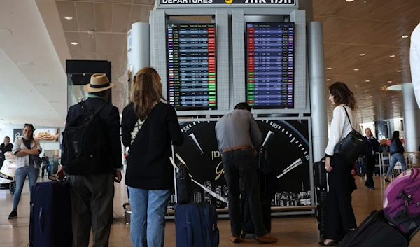 Israeli settlers and passangers look at the monitor displaying delayed flights at Ben Gurion airport, near Tel Aviv, 'Israel', Monday, March 27, 2023. (AP)